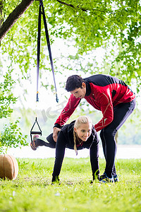 弹力带运动摄影照片_男人和女人在健身训练中做俯卧撑