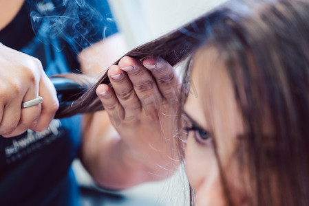 理发师在女顾客的头发上使用扁铁