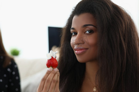 新鲜的草莓水果摄影照片_拉丁女人拿着新鲜的草莓水果，上面放着生奶油
