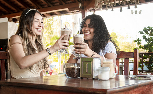 友情摄影照片_两个女孩喝奶昔，两个女朋友在咖啡馆，两个女孩在咖啡馆敬酒