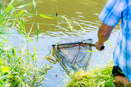 运动钓鱼者用浸液将捕获物从水中捞出