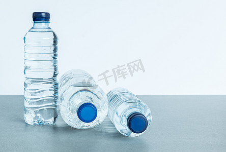 蓝色的矿泉水瓶子摄影照片_白色背景中三个装满矿泉水的塑料瓶
