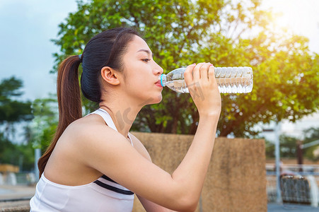 运动型年轻女子慢跑后喝水。