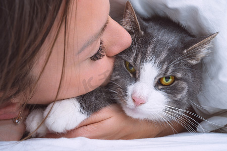 美丽的女人亲吻滑稽的脾气暴躁的猫。