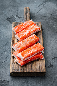 蟹摄影照片_蟹棒海鲜半成品鱼肉末与蓝色游蟹，在木切板上，灰色背景