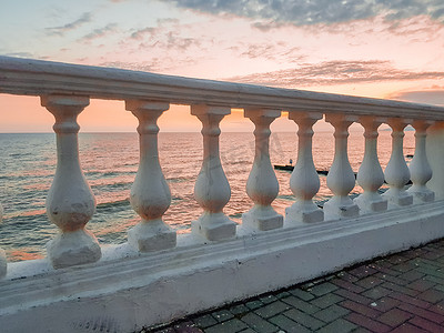 日落时平静的大海背景上经典的白色石膏栏杆 — 微妙的粉红色心情