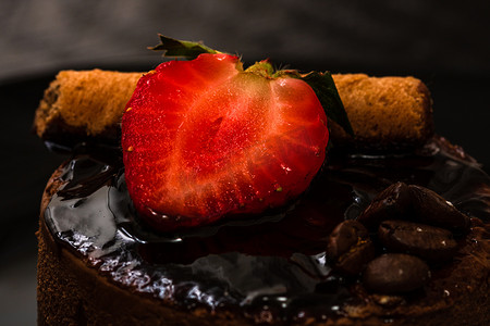 巧克力慕斯蛋糕摄影照片_巧克力慕斯配草莓和巧克力棒在黑色的盘子上。