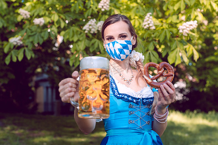 举杯啤酒摄影照片_巴伐利亚妇女在 covid-19 期间举杯啤酒