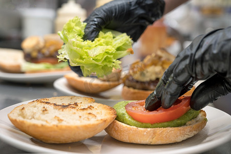 厨师烹饪汉堡，特写，制作三明治，快餐概念，用蔬菜准备自制汉堡的食谱。
