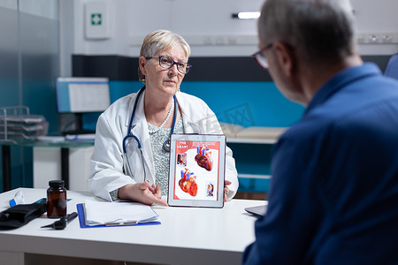 医生用平板电脑上的心脏器官图像向患者解释心脏病学诊断