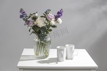 玻璃花瓶中的哈克利亚绒毛花、紫色和白色玫瑰、小茶玫瑰、matthiola incana 和蓝色鸢尾花束