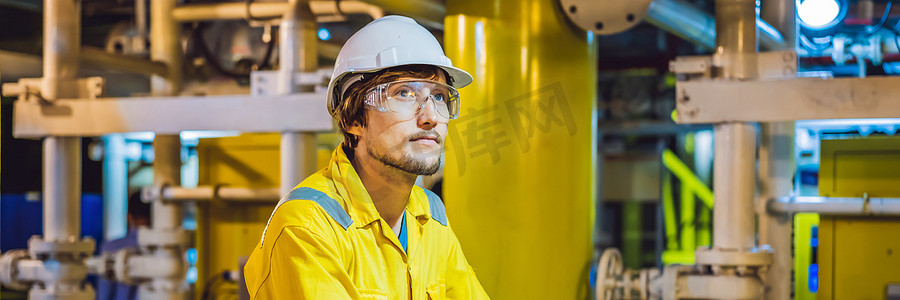 工业环境、石油平台或液化天然气厂横幅、长格式中穿着黄色工作服、眼镜和头盔的年轻人