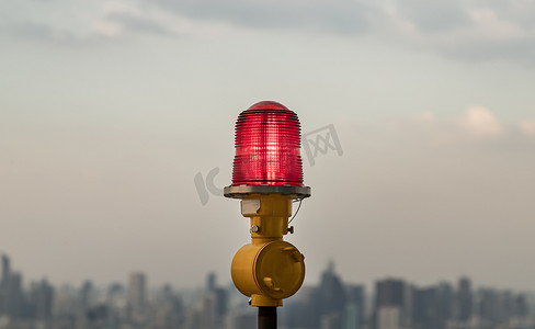 高层建筑屋顶安装障碍灯红灯笼，确保飞行安全，并在城市景观背景下警告飞机危险。