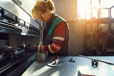 在现代化工厂工作并为数控机床准备材料的妇女。