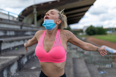 女性在户外训练或跑步后摘下医用口罩