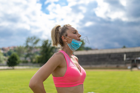 摘口罩摄影照片_女性在户外训练或跑步后摘下医用口罩