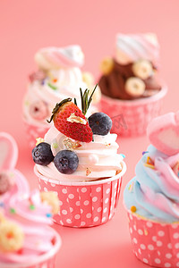 粉红色背景中孤立的彩色纸杯蛋糕