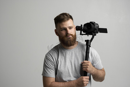 专业的大胡子摄影师拿着设置在 3 轴万向节上的相机。
