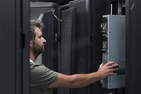 在服务器机房或数据中心工作的 IT 工程师技术人员将企业业务大型机超级计算机或加密货币采矿场的新服务器放入机架中。