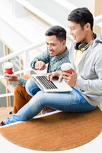 鼠摄影照片_两名年轻的亚洲男子在休息期间放松时使用笔记本电脑
