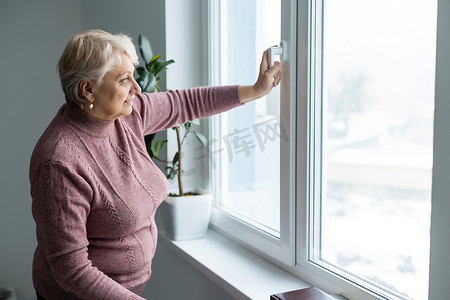 站在家窗前的老年妇女的肖像