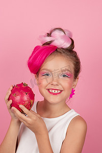 可爱的女孩在她的脸附近拿着一个火龙果。