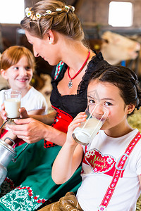 牛仔喝酒摄影照片_巴伐利亚家庭在牛棚里喝牛奶