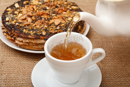 茶从瓷茶壶倒入杯子，配有自制巧克力蛋糕