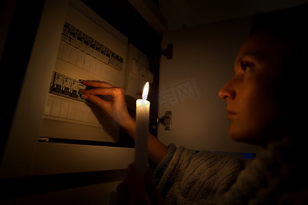 在停电或停电期间，妇女在完全黑暗中检查家里的保险丝盒。