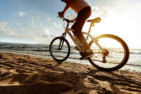 一名男子在沙滩上骑自行车的图像。