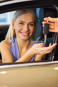 快乐的女人在车展或沙龙里拿到车钥匙