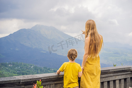 旅游活动中摄影照片_母子游客在背景中观看巴杜尔火山。