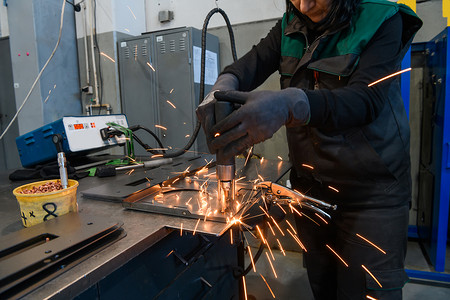 一位在现代金属生产和加工行业工作的女性焊接产品并为数控机床做好准备