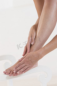 用修剪过的指甲按摩脚和脚踝的女人