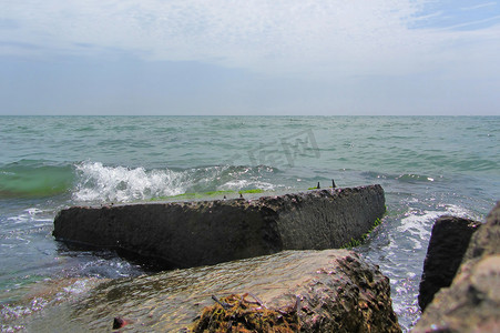 海浪拍打着码头上长满绿藻的方形岩石。