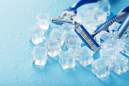 三台剃须机在冷淡的蓝色背景上加冰。