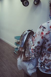变化过程摄影照片_女人在理发店染发，用箔纸染发的过程。