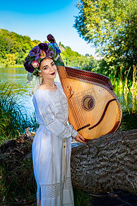 夏日阳光明媚的日子，身着民族服饰的乌克兰年轻女子在河边演奏班杜拉