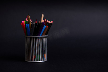 代表钢笔和铅笔在桌面上的黑色背景与复制空间。
