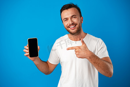 年轻人为新智能手机做广告的肖像，在蓝色背景下向相机展示