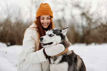 年轻女子带着哈士奇在雪地里散步玩耍休息新鲜空气