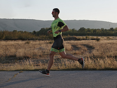 晨间跑步摄影照片_铁人三项运动员在晨间训练中跑步