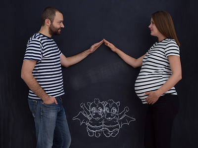 怀孕夫妇在黑板上画出他们的想象力