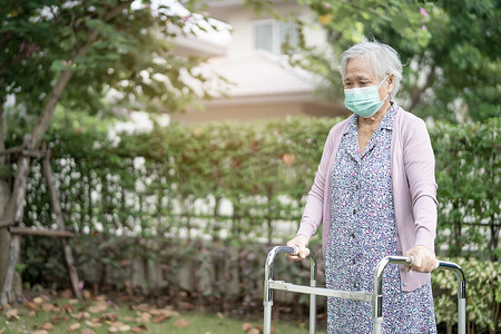亚洲老年或老年老妇人与助行器一起行走，戴着口罩，以保护安全感染并杀死新型冠状病毒Covid-19病毒。