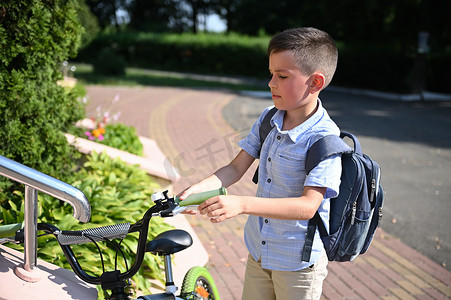 男学生将自行车停在学校入口处。
