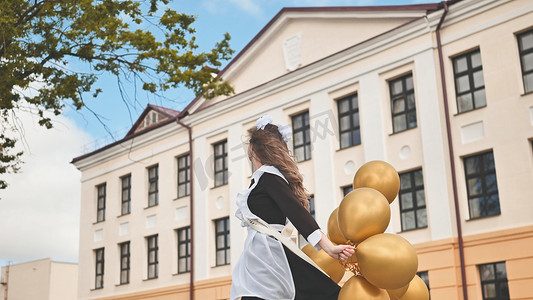 快乐的俄罗斯女学生在学校的最后一天带着气球。