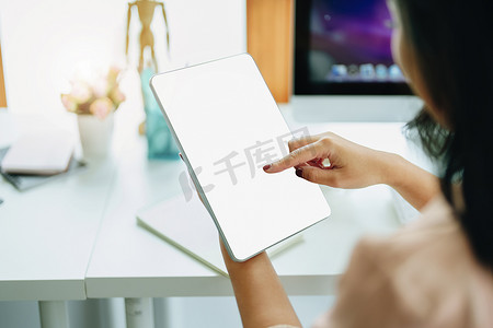 年轻女性使用家庭平板电脑工作，以避免在公司工作时感染冠状病毒的风险，平板电脑屏幕上的空白区域可以插入文本。