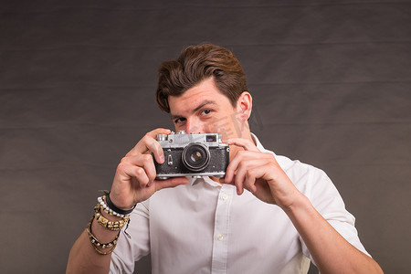 技术、摄影和爱好概念 — 带复古相机的男人，在灰色背景下给你拍照