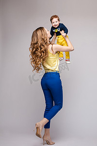 孩子抱妈妈摄影照片_年轻而健康的女人穿着休闲服抱着小孩。