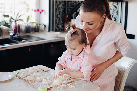 面粉做饭摄影照片_从女人和可爱的女儿一起做饭的侧面看